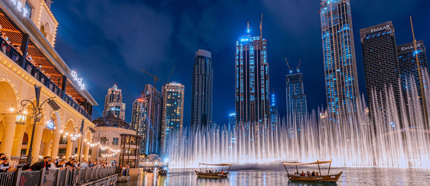 The Dubai Fountain performing a water and light show at night in front of the illuminated Burj Khalifa