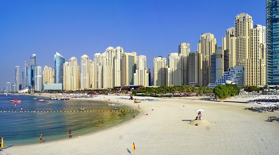 Sunbathers on JBR public beach with the Dubai Marina skyscrapers in the background